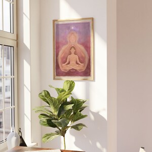 May include: A framed print of a watercolor painting depicting a woman meditating with a glowing aura. The woman is sitting in a lotus position with her eyes closed. The background is a soft purple and pink gradient with a single white star at the top.