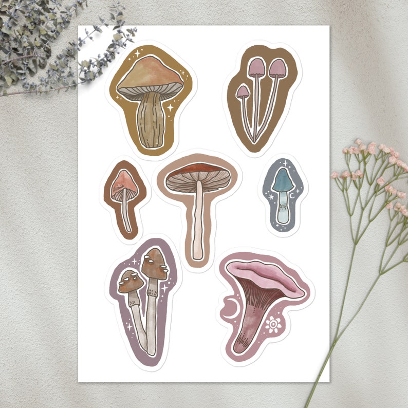 May include: A set of ten mushroom-shaped stickers in various colours and styles. The stickers feature different mushroom shapes, including a cluster of mushrooms, a single mushroom with a brown cap, and a mushroom with a pink cap. The stickers are perfect for adding a touch of whimsy to journals, laptops, water bottles, and more.