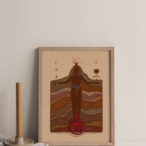 May include: A framed print of a stylised illustration of a woman standing with her arms outstretched. The woman is depicted as a cross-section of the earth, with layers of brown, red, and orange representing the different layers of the earth. The woman's heart is depicted as a red circle, and her head is a red volcano erupting with red lava. The print is on a beige background and has a wooden frame.