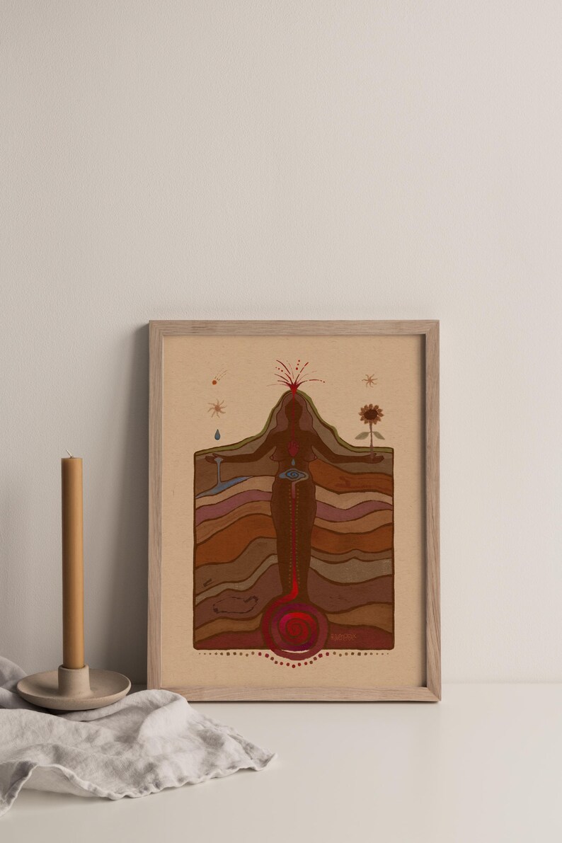 May include: A framed print of a stylised illustration of a woman standing with her arms outstretched. The woman is depicted as a cross-section of the earth, with layers of brown, red, and orange representing the different layers of the earth. The woman's heart is depicted as a red circle, and her head is a red volcano erupting with red lava. The print is on a beige background and has a wooden frame.