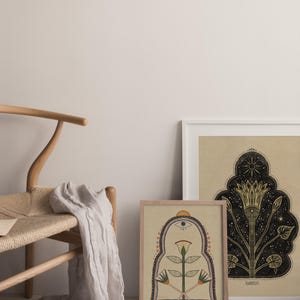 May include: Two framed illustrations with a beige background. The illustration on the left features a stylized flower with a third eye and a geometric archway. The illustration on the right features a stylized flower with a star and a crescent moon.