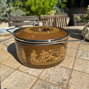 May include: A brown enamel pot with a silver lid and handle. The pot has a gold design of Greek warriors and a decorative border around the top.