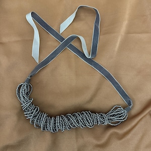 May include: A silver beaded necklace with a gray velvet ribbon.