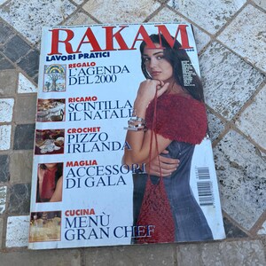 Op de afbeelding: Een tijdschriftcover met een vrouw die een rood gebreid topje en een spijkerrok draagt. Het tijdschrift heet "Rakam" en bevat de tekst "Lavorri Pratici" en "Regalo L'Agenda Del 2000".