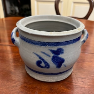 May include: A blue and white ceramic crock with a lid and two handles. The crock has a blue and white floral design.