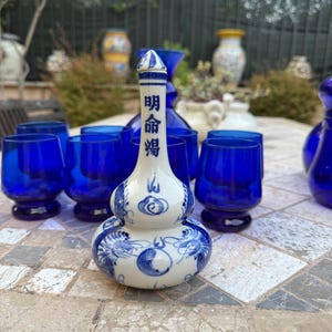 Piccola bottiglia vino o sakè orientale met drago en nuvole, bianca en blu con tappo.