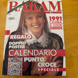 May include: A magazine cover featuring a woman with blonde hair and a white shirt. The magazine is titled "Rakam" and has the words "Lavorri Pratici" and "1991 Cambia Il Look Correde" printed on the cover. The magazine also has the words "Regalo Doppio Poster Calendario Punto Croce Speciale" printed on the cover.