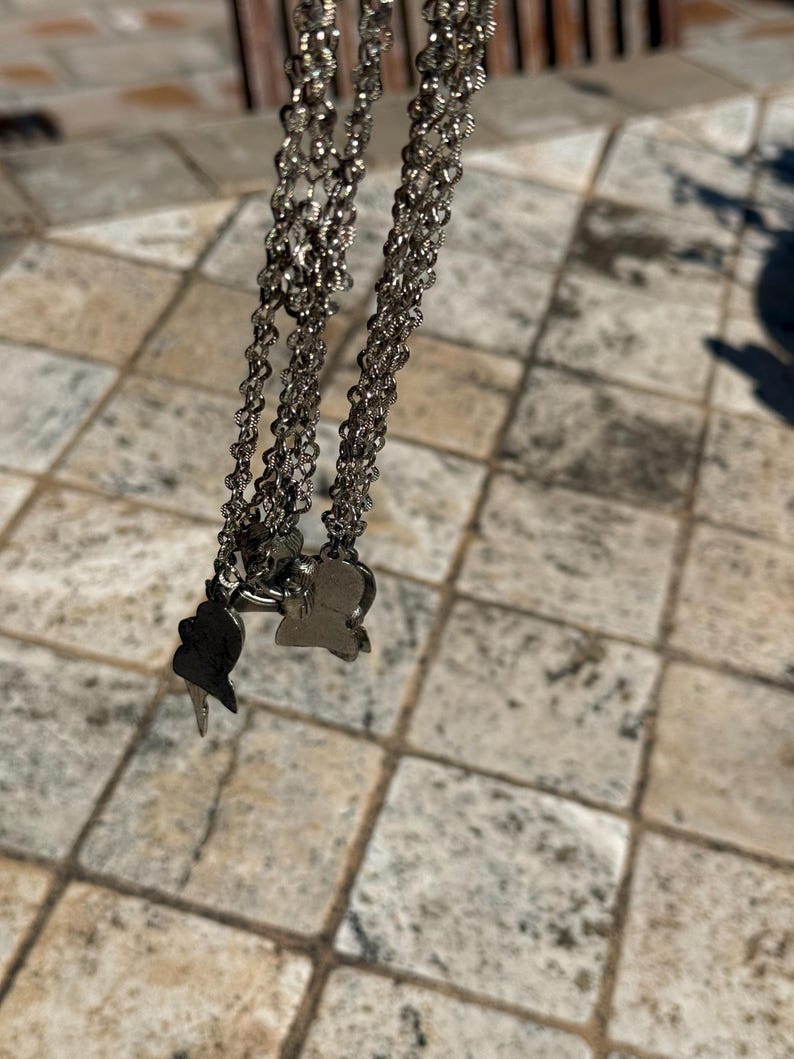 May include: Silver-toned layered necklace with small, delicate chains. The necklace features two pendant charms, one shaped like a butterfly and the other like a bird. The jewelry is displayed against a neutral background.