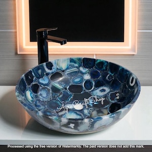 May include: Oval-shaped bathroom sink with a mosaic design of blue and white stones. A black faucet is mounted above the sink. The sink is a decorative element for a bathroom.