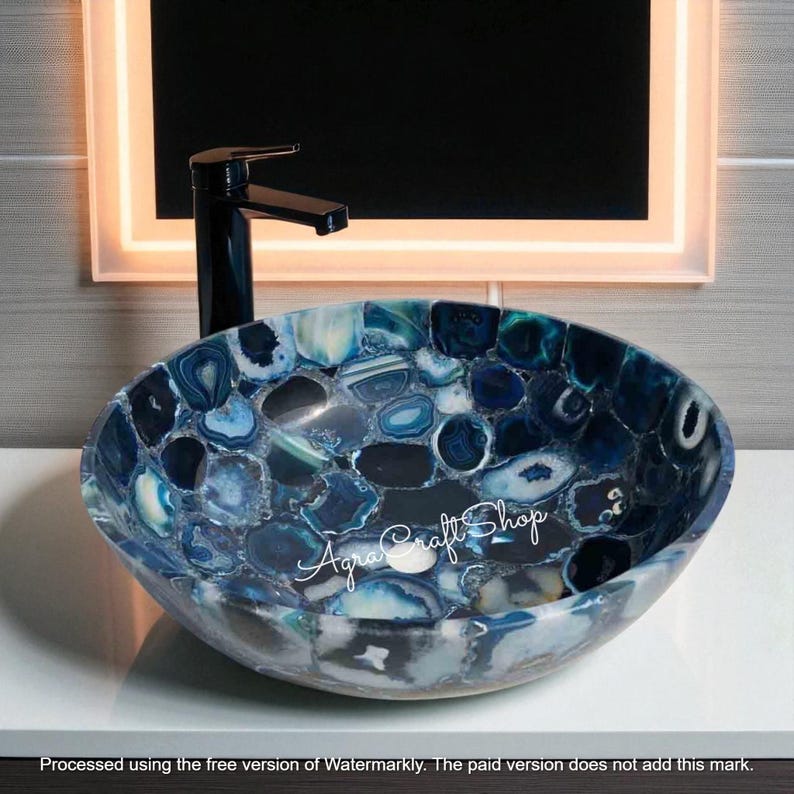 May include: Oval-shaped bathroom sink with a mosaic design of blue and white stones. A black faucet is mounted above the sink. The sink is a decorative element for a bathroom.