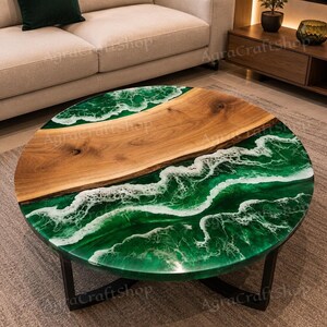 Peut inclure: Table basse ronde au design unique. Elle présente une section en bois et une section en résine époxy verte imitant les vagues de l'océan. La table repose sur un socle en métal noir et est posée sur un tapis de couleur neutre. Diamètre: environ 100 cm.