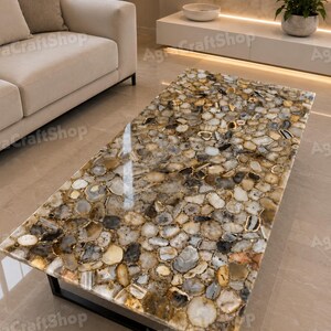 May include: Rectangular coffee table with a polished, mosaic-like surface composed of various-sized, irregularly shaped stones in shades of brown, beige, and gray. The table is supported by a black metal frame, adding a modern touch to the natural stone design.