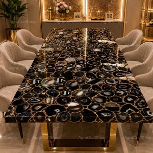 May include: A rectangular dining table featuring a polished surface made of inlaid black agate slices with white and grey banding, supported by a gold-toned metal base, surrounded by six upholstered beige chairs with vertical channel tufting.