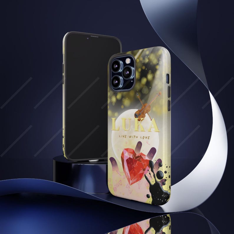 May include: A phone case with a design featuring a red heart, a violin, and the name "LUKA" in gold lettering. The case has a yellow and black background with the words "LIVE WITH LOVE". A second phone is visible.