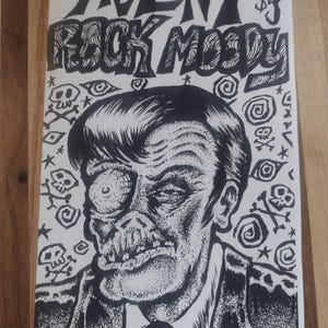 May include: Black and white comic book cover featuring the title "AGENT ROCK MOODY" above a detailed illustration of a grotesque, zombie-like man. The background is filled with skulls, stars, and spiral designs.