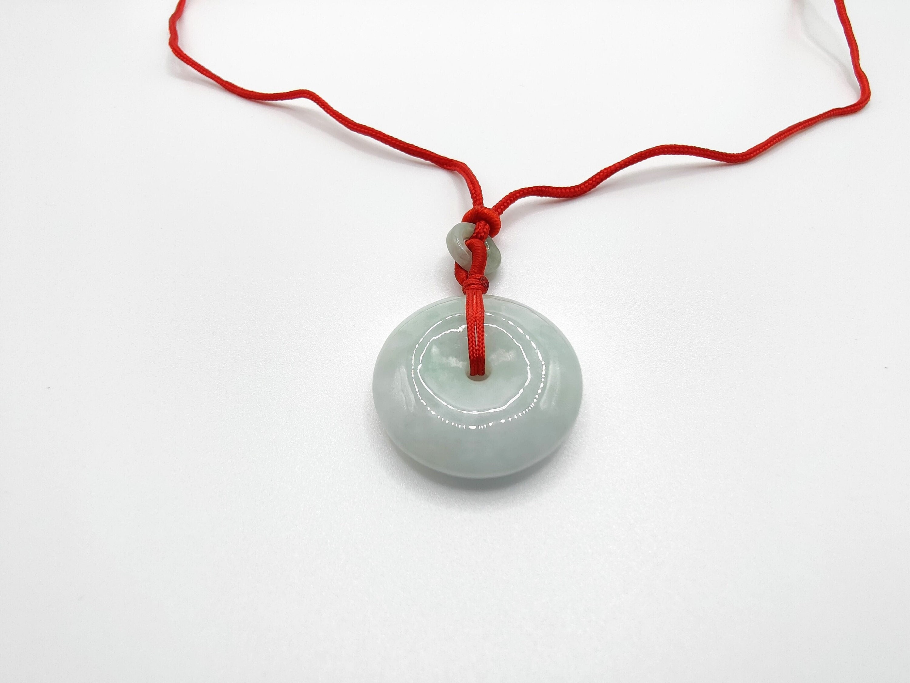 An Istone Chinese jade pendant, depicting a Buddha, on red string strand,  4.5cm high, with