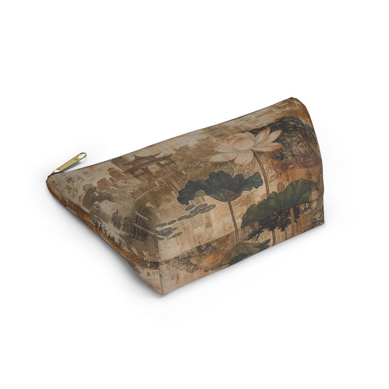 May include: A rectangular cosmetic bag with a gold zipper. The bag features a vintage-style print of a lotus flower, leaves, and an Asian-inspired landscape in shades of brown, beige, and green.
