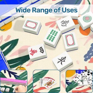 Pode incluir: Pe&ccedil;as de Mahjong brancas com v&aacute;rios s&iacute;mbolos e bordas coloridas est&atilde;o espalhadas em uma superf&iacute;cie com estampa floral. O texto "Wide Range of Uses" &eacute; exibido na parte superior. Imagens adicionais mostram cartas de baralho, domin&oacute;s e mais pe&ccedil;as de Mahjong.