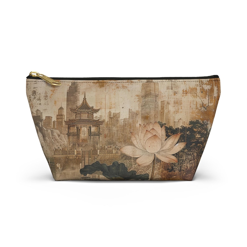 May include: A beige cosmetic bag featuring an Asian-inspired design. The bag displays a lotus flower and a pagoda with a cityscape backdrop. It has a gold zipper and a black trim.