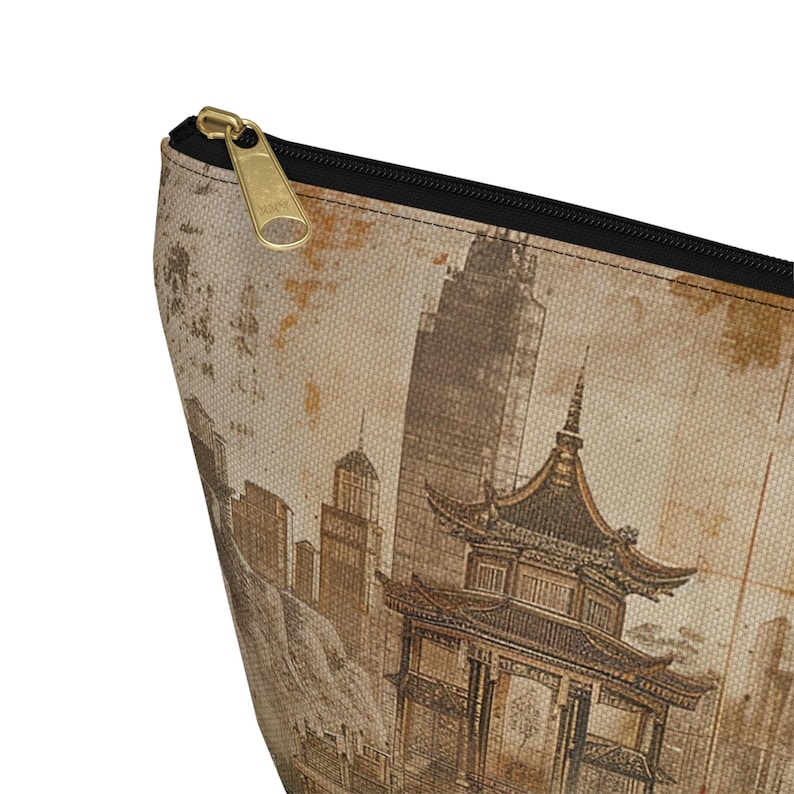 May include: A beige zippered pouch featuring a sepia-toned illustration of a cityscape with a pagoda and skyscrapers. The pouch has a black zipper and a gold-colored zipper pull. The design has a vintage, travel-inspired aesthetic.