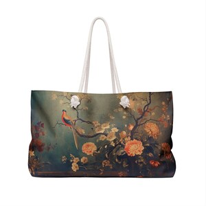 May include: Large tote bag featuring a vintage-style floral and bird design. The bag has a cream-colored rope handle and a rectangular shape. The artwork includes a bird perched on a branch with orange and yellow flowers.