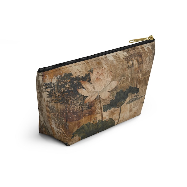 May include: A beige cosmetic bag with a black zipper and gold-colored pull. The bag features a vintage-style print of a lotus flower, leaves, and a landscape scene in shades of brown and green.