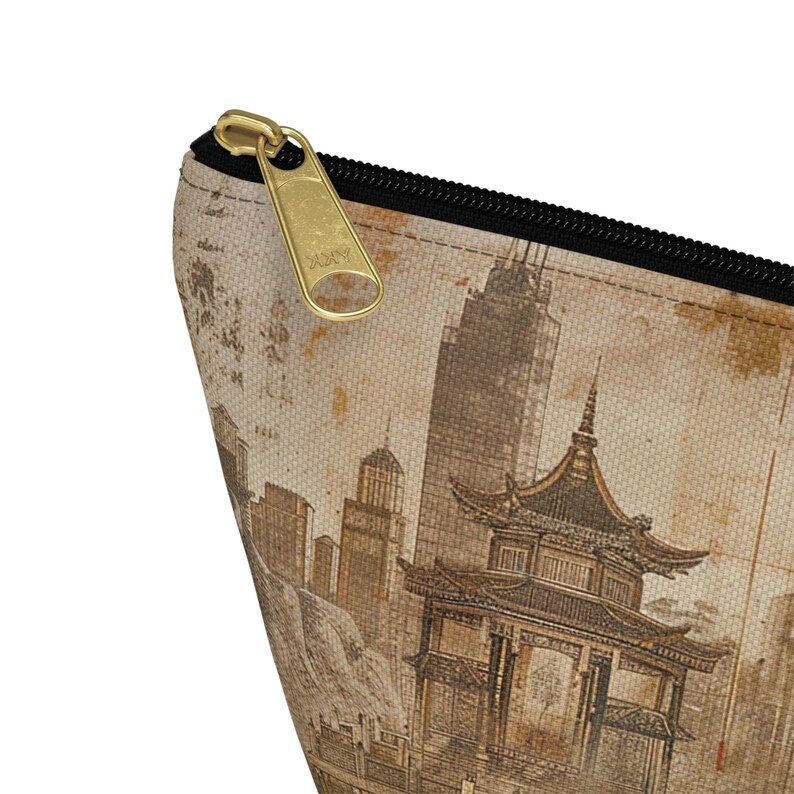 May include: A beige zippered pouch featuring a vintage-style illustration of a pagoda and city skyline. The design is in shades of brown and tan, with a gold-colored zipper and black trim. The pouch is likely made of canvas or a similar fabric.