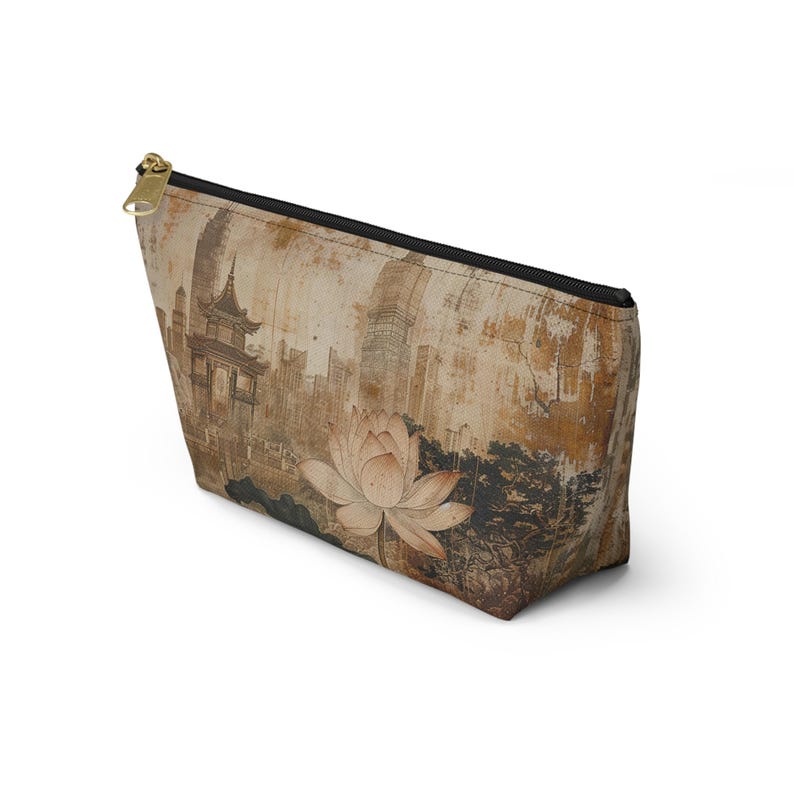 May include: A beige cosmetic bag with a black zipper and gold-colored pull. The bag features a vintage-style print of a lotus flower and a cityscape in shades of brown and beige.