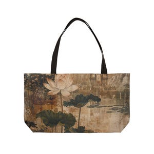 May include: Tote bag featuring a serene Asian-inspired painting of a lotus flower and lily pads. The artwork is in muted tones of beige, brown, and green, with a black handle. The bag is designed for carrying items.