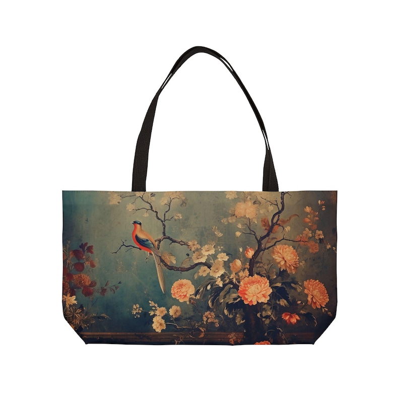 May include: Tote bag featuring a vintage-style illustration of a bird perched on a flowering branch. The design includes peach-colored flowers and a teal background. The bag has black handles.