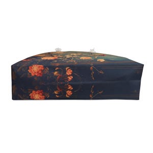 May include: A large tote bag with a dark blue background and a floral pattern featuring orange and yellow flowers. The bag has white rope handles and is designed for carrying items.