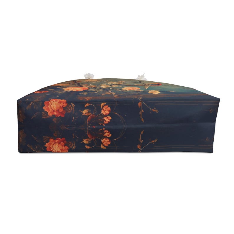 May include: A large tote bag with a dark blue background and a floral pattern featuring orange and yellow flowers. The bag has white rope handles and is designed for carrying items.