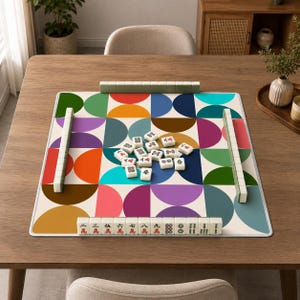 Pu&ograve; includere: Un tappetino da mahjong quadrato con un colorato motivo geometrico a semicerchi rossi, arancioni, gialli, viola, blu e verdi. Il tappetino &egrave; disposto con quattro file di tessere bianche da mahjong e altre tessere sparse al centro.