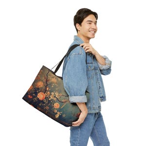 May include: Large tote bag featuring a floral design with orange and white blossoms on a teal background. The tote bag has black straps and is carried over the shoulder. The bag's design includes branches and a bird.