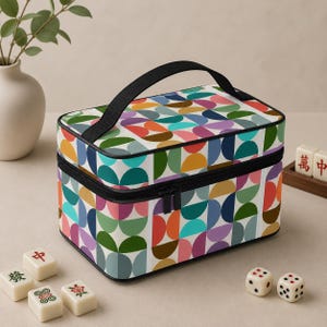 May include: A rectangular storage case with a black handle and zipper closure, featuring a repeating pattern of multicolored semicircles in shades of orange, teal, blue, pink, and green on a white background, surrounded by scattered mahjong tiles.