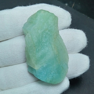 May include: A large, rough, light blue aquamarine crystal with a translucent, glassy appearance.