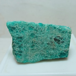 May include: A raw, unpolished mineral specimen featuring a vibrant teal-green colour with a textured, crystalline surface. The stone displays natural variations in shade, ranging from light mint to deep forest green, with visible inclusions.