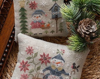 May include: Two embroidered cushion covers featuring winter scenes with snowmen. The top cushion cover shows a snowman holding a birdhouse and the bottom cushion cover shows a snowman holding a walking stick.