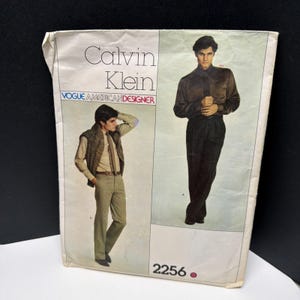 Könnte beinhalten: Eine Vogue American Designer Schnittmusterhülle für Calvin Klein Entwürfe mit der Nummer 2256. Die Vorderseite zeigt Illustrationen von zwei Outfits: eines mit einer strukturierten Weste über einem Hemd und einer Hose, und ein weiteres mit einem langärmeligen Hemd und einer Hose.
