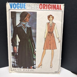 May include: A Vogue Paris Original sewing pattern envelope for Jean Patou design 2937. The front features a photograph of a dark green coat with a light blue scarf and a fashion illustration of a peach-colored sleeveless dress with a white shirt.