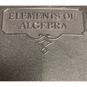 May include: A black leather-bound book with the title "Elements of Algebra" embossed on the front cover.