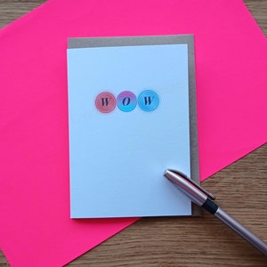 May include: A white card with the word "WOW" spelled out in colourful circles. The circles are red, blue, and pink.