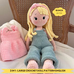 Puede incluir: Una muñeca de ganchillo hecha a mano con cabello rubio y un peto azul, de aproximadamente 45 cm de altura, está sentada junto a un vestido rosa de ganchillo. La muñeca tiene una diadema rosa. El texto de la imagen dice "2 IN 1 - LARGE CROCHET DOLL PATTERN ENGLISH."