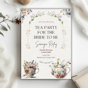 Può includere: Un invito a un tea party floreale per Somaya Rafiq. L'invito presenta una teiera e una tazza da tè con motivi floreali e il testo "Tea Party for the Bride-to-Be" in caratteri neri. La data e la posizione della festa sono anche incluse.