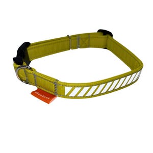 May include: A yellow dog collar with a reflective white stripe pattern and a black buckle. The collar has a small orange tag that says "Mudless".