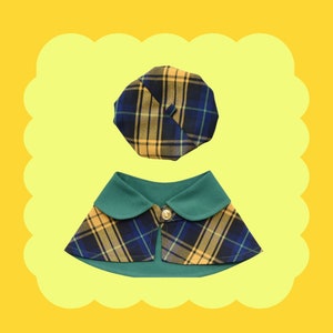 May include: A plaid dog collar with a matching plaid beret. The collar is green with yellow and blue plaid, and the beret is yellow with blue and green plaid.