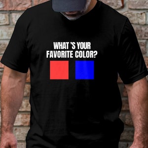 Peut inclure: Un t-shirt noir avec le texte "What's your favorite color?" imprimé en blanc. Deux carrés, un rouge et un bleu, sont affichés sous le texte.