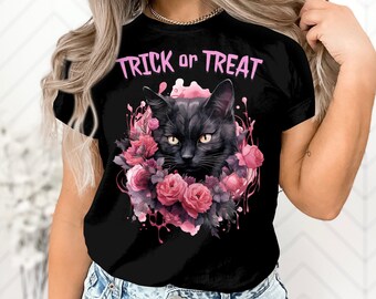 Puede incluir: Camiseta negra con un diseño que presenta un gato negro con ojos amarillos, rosas rosas y las palabras "Trick or Treat" en rosa. El diseño tiene un efecto acuarela.