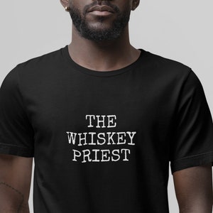 May include: A black t-shirt with white text that reads "THE WHISKEY PRIEST".