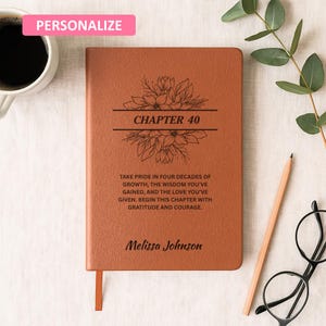 Peut inclure: Un journal en cuir marron personnalisé avec le texte "CHAPITRE 40" et un motif floral. Le journal comprend le texte "Soyez fier de quatre décennies de croissance..." et le nom "Melissa Johnson". Une étiquette rose "PERSONNALISER" est en haut à gauche.